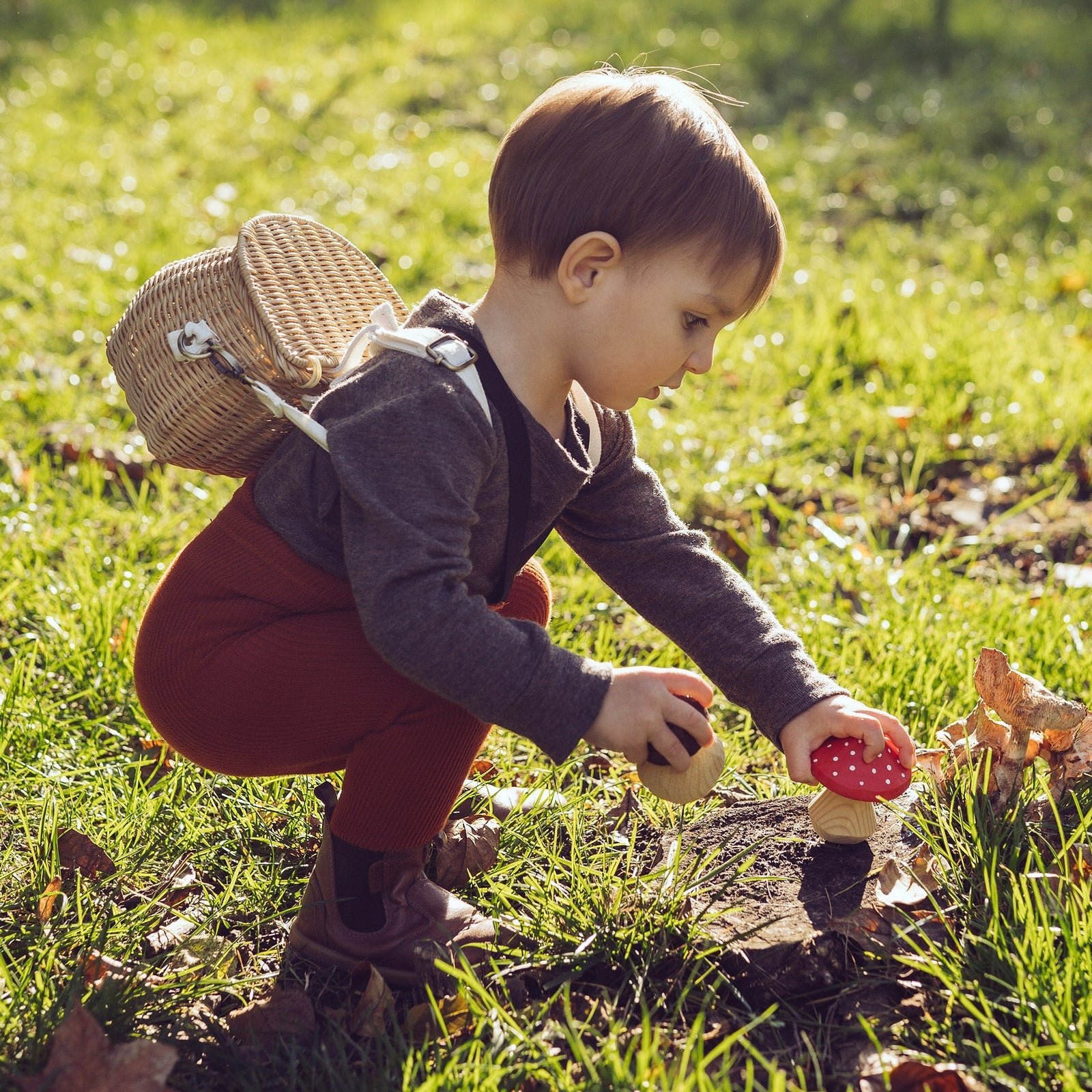 A little boy wearing Peqne tights with suspenders, playing outside.